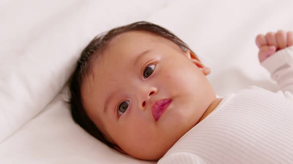 happy newborn baby lying on a white bed and blanket comfortable and safety