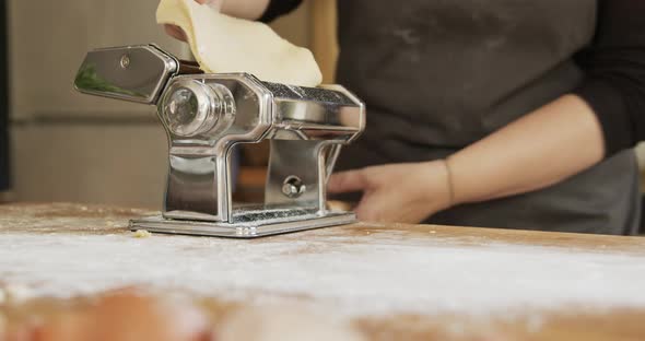 Woman using pasta machine while making dough for Maultaschen