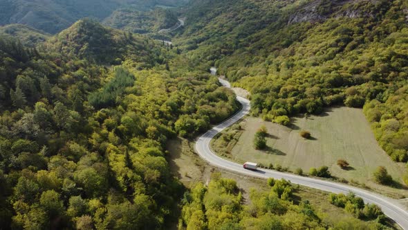 The truck is going on the winding road aerial view