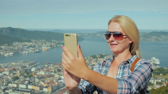 Woman Tourist Taking Pictures of Herself Against the Background of the City of Bergen in Norway