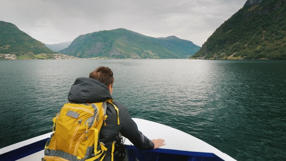 A Man with a Backpack Travels Through a Picturesque Fjord in Norway
