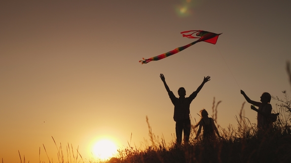 Family with a Child Playing with a Kite. In a Picturesque Place at Sunset