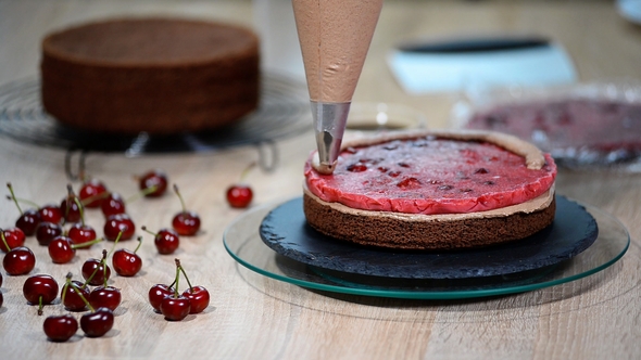 Unrecognizable Female Pastry Cook Squeezing Chocolate Cream on Appetizing Layer Cake in Kitchen