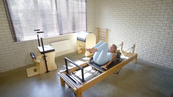 Young Girl Learn To Perform Exercises on Pilates Simulator in Home Sports Studio