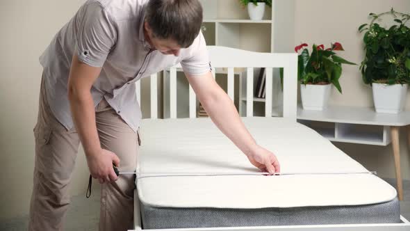 A Man Measures with a Tape Measure the Width of an Orthopedic Mattress