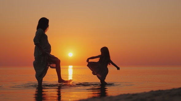 Pregnant Woman with Her Daughter Having Fun on the Beach