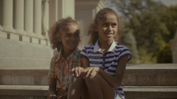 Two Adorable Little Girls Relaxing on Stairs
