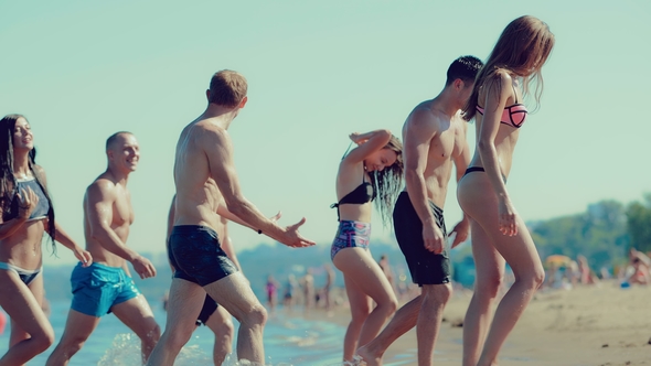 Group of Friends Coming Out of the Water on the Beach. Side View