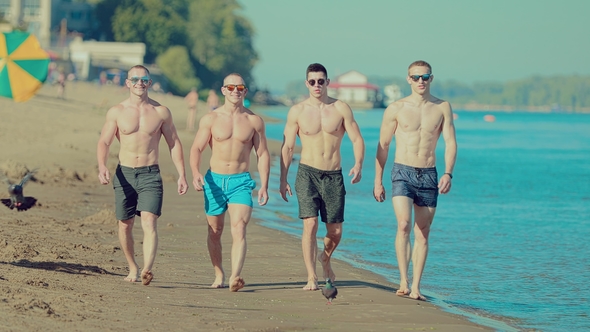 Beautiful, Young and Athletic Guys Are Walking Along the Beach. Front View