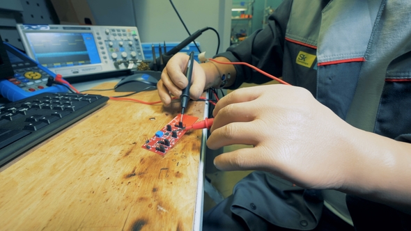 Man with Prosthetic Hands Is Soldering a Microscheme