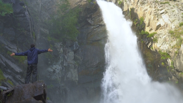 The Traveler Stands Next To the Waterfall.