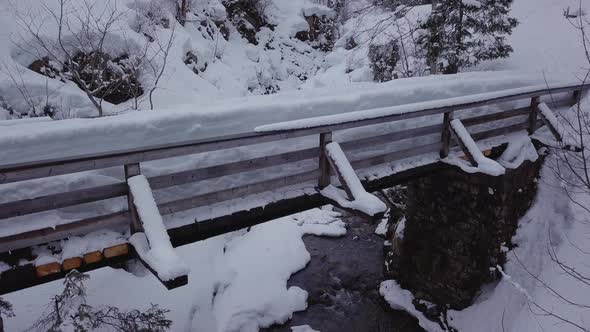 Winter wonderland.Snowy valley with a creek in the alps. Drone is descending in front of a bridge in