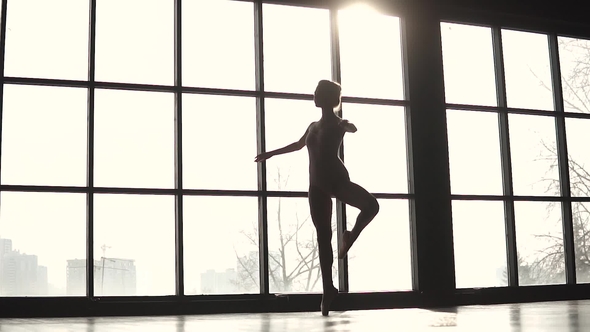 Silhouette Graceful Ballerina on the Background of a Large Window. Ballet Dancer in Pointe Shoes