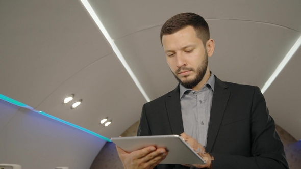 Young Bearded Lawyer Businessman in Working Process, Using Tablet in Personal Airplane