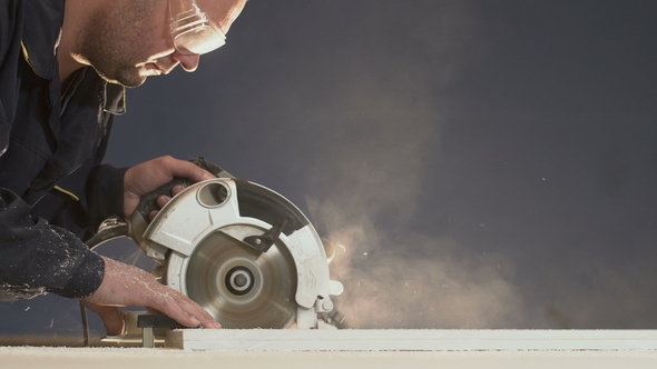 Shavings and Dust Fly Away When Worker Small Circular Saw Is Processing Tree