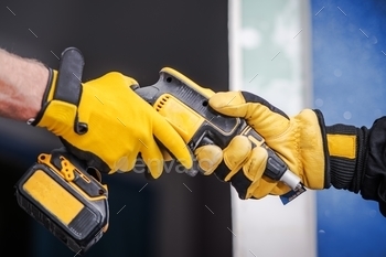 tors in Safety Gloves. Closeup Photo. Drill Driver.