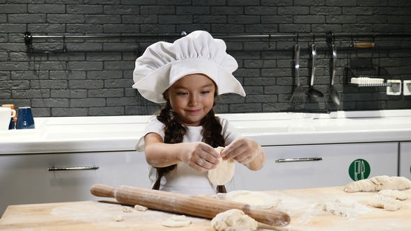 Little Pretty Girl in Chef Hat and Apron. Kid Chef Concept. Adorable Girl Playing with Dough