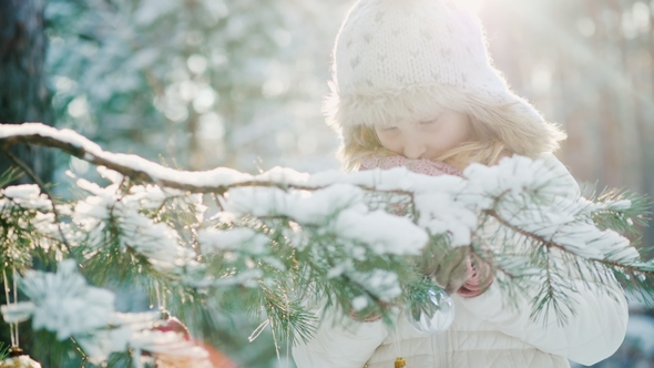 The Little Girl in a Warm Knitted Hat Prepares for Christmas, Decorates the New Year Tree with