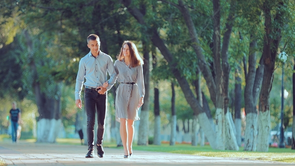 Young Couple Walking Along the City Park Together, Go To the Camera