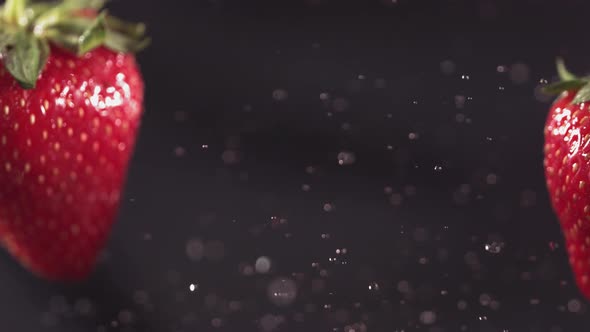 Two Big Strawberries are Flying and Colliding on a Black Background