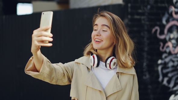 Cheerful Blonde Is Making Video Call, Talking and Laughing Looking at Smartphone Screen