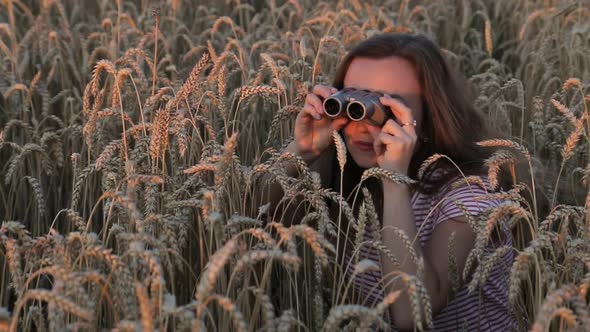 Beautiful Young Girl Looking Through Binoculars On Blue Sky Background.