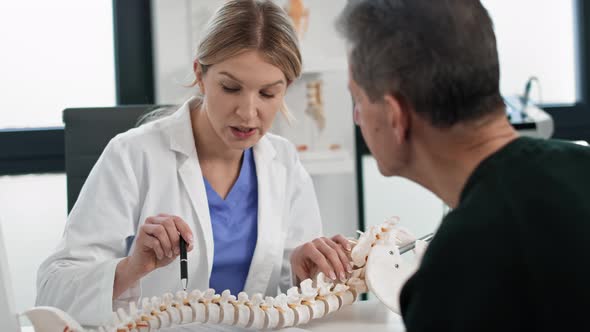 Caucasian senior man with female doctor talking about spine at the office. Shot with RED helium came