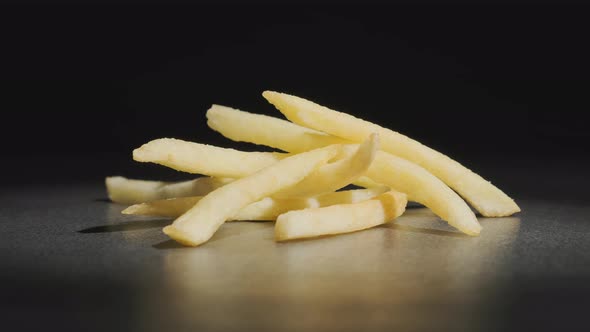 golden French fries rotating on table on black background