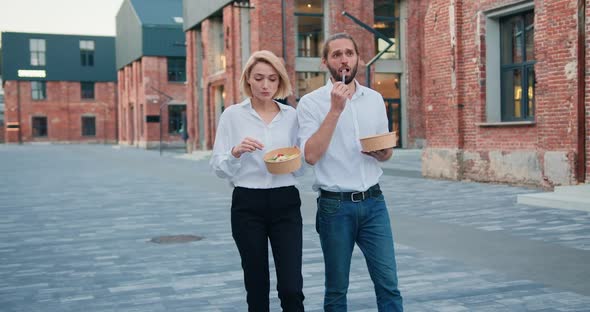 Man and Woman Office Workers in white Shirts Eating Salad and Having Fun Chatting While Walking