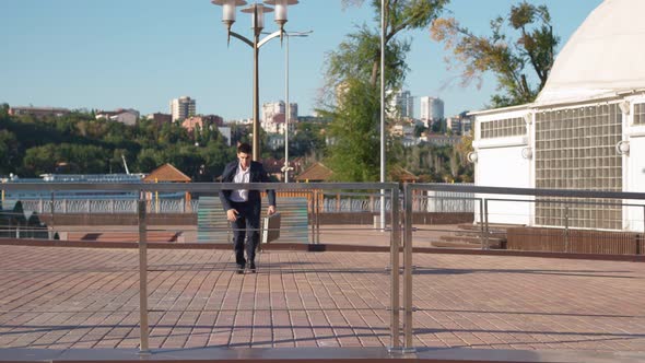 Businessman Runs with Business Briefcase in His Hands and Overcomes an Obstacle