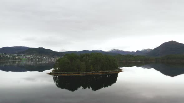 Small Green Forest Island In The Middle of a Lake in Norwegian Nature. - aerial orbit, drone shot