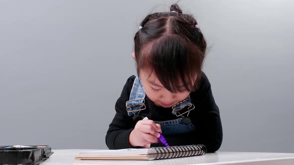 Child choosing black pen in the full case for drawing. Image produced in the studio with a gray back