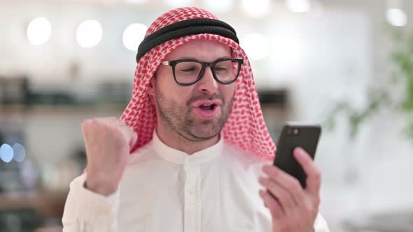 Excited Young Arab Businessman Celebrating Success on Smartphone 