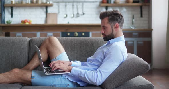 Relaxed Serious Freelancer Using Laptop Device Leaning on Sofa at Home Office Focused Entrepreneur
