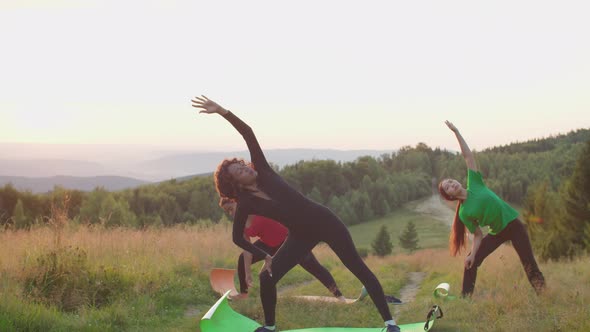 Lovely Active Sporty Multicultural Females Practicing Standing Side Bending Yoga Pose in Mountains