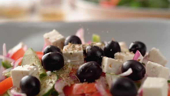 Camera follows putting salt over greek salad. Slow Motion. alt