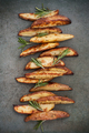 Slices of baked potatoes with rosemary on a textured stone table - PhotoDune Item for Sale