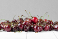 A handful of red cherries on a white wooden table in a crisp pla - PhotoDune Item for Sale