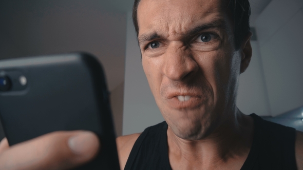 Angry Man Aggressively Uses Smartphone at Home in the Kitchen