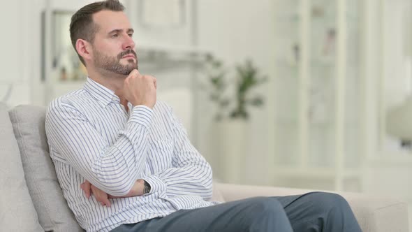 Pensive Young Man Sitting at Home and Thinking 