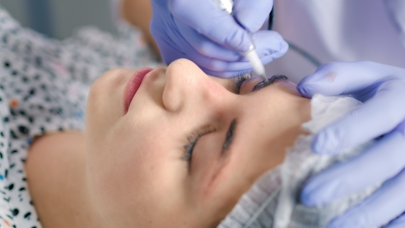 Cosmetologist Making Microblading Procedure Working with Eyebrows