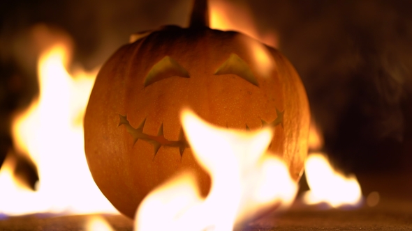Smiling Happy Carved Halloween Pumpkin Against of Fiery Explosion Background. Glowing Face Trick or