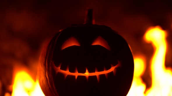 Black Smiling Happy Carved Halloween Pumpkin Against of Fiery Explosion Background. Glowing Face