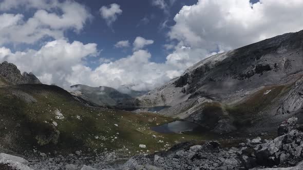 Timelapse of clouds and shadows over a beautiful valley with talus rocks and lakes.