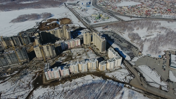 Construction of a New Residential Area in Front of Road Traffic Covered in Snow