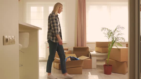 A Woman Takes Out Cardboard Boxes with Things From an Old House