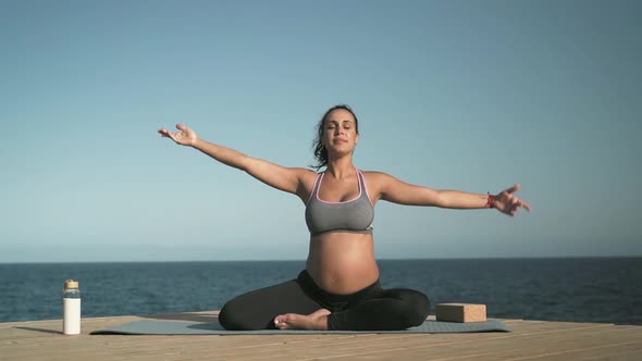 Young pregnant woman doing yoga meditation outdoor - Body balance and pregnancy concept