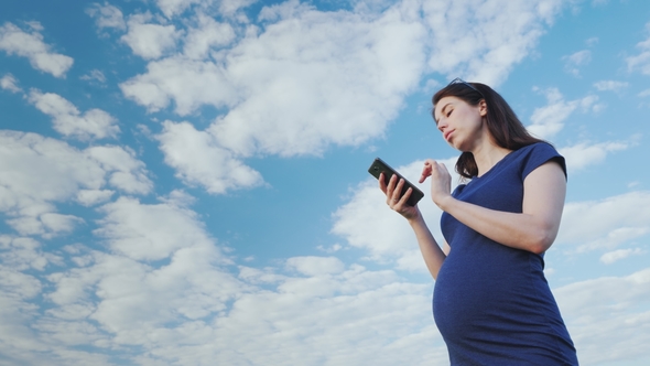 Pregnant Woman Taking a Picture Against the Blue Sky