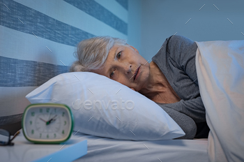 m insomnia. Old woman lying in bed with open eyes. Mature woman unable to sleep at home.