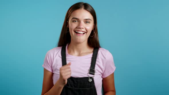 Beautiful Woman Dancing Energetically and Actively on Blue Studio Background. Cute Girl in Black